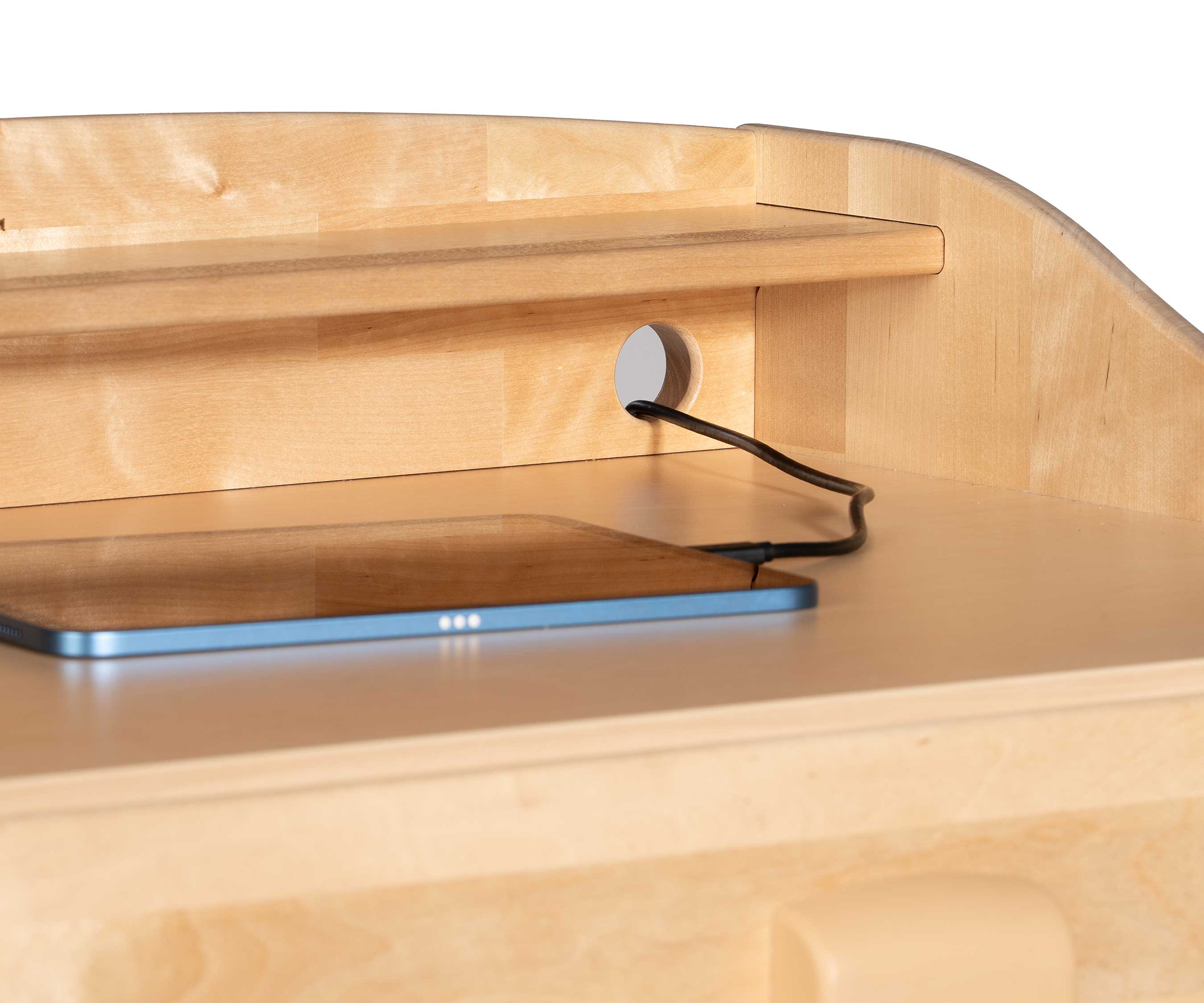 Ein Tablet auf der Schreibfläche eines Stehpults, dessen Ladekabel durch einen der Kabelanschlüsse des Stehpults verläuft