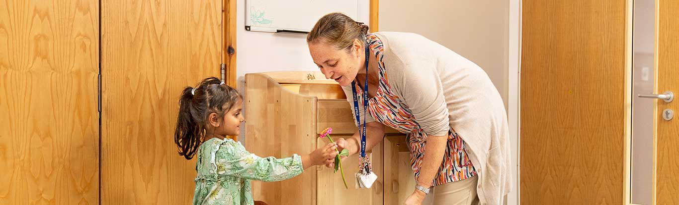 Eine Erzieherin interagiert mit einem Kind vor einem Stehpult