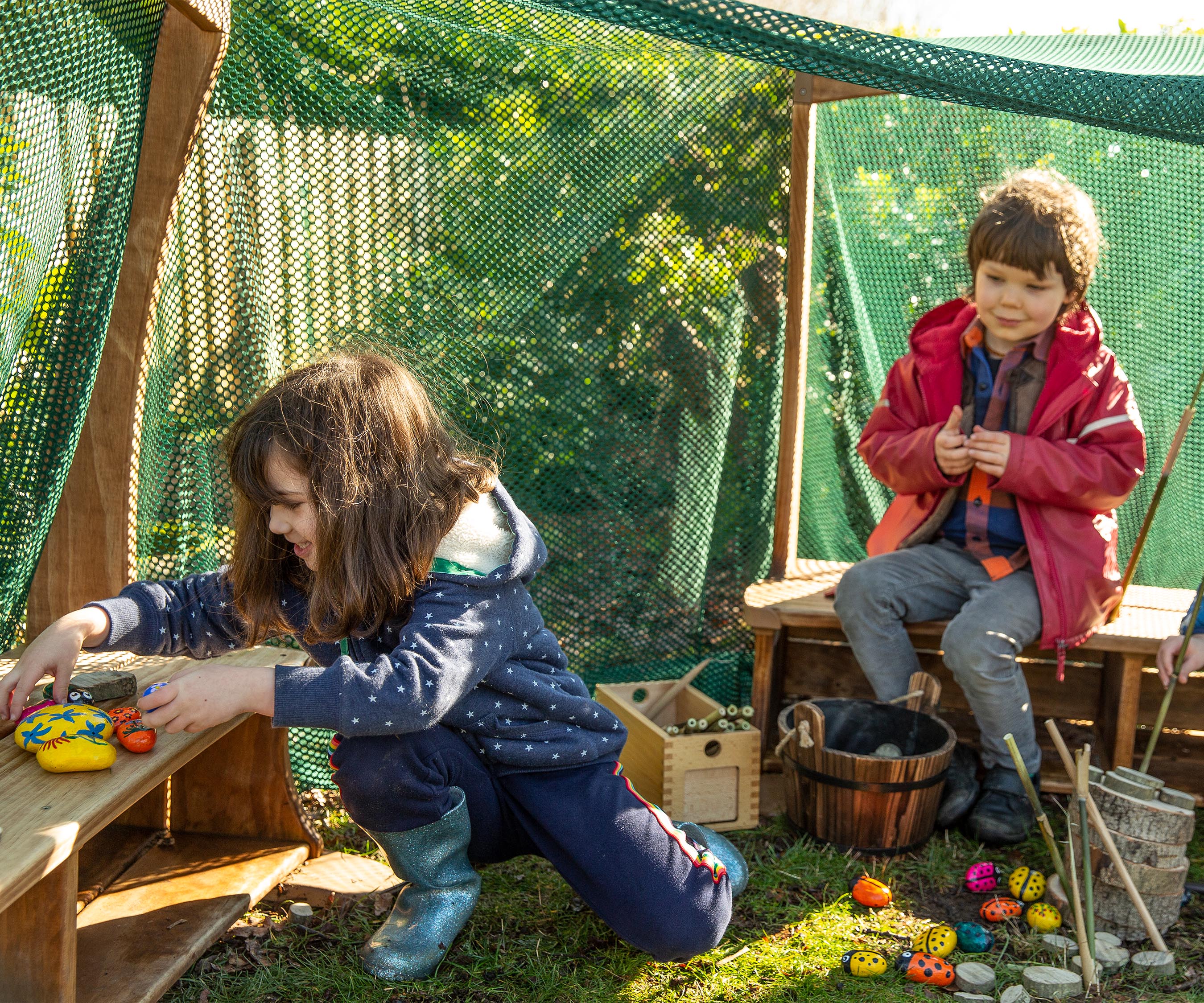 A reception aged boy and girl playing under an Outlast arbour