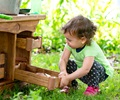 A toddler is using a Nature tray with a toddler mud kitchen unit