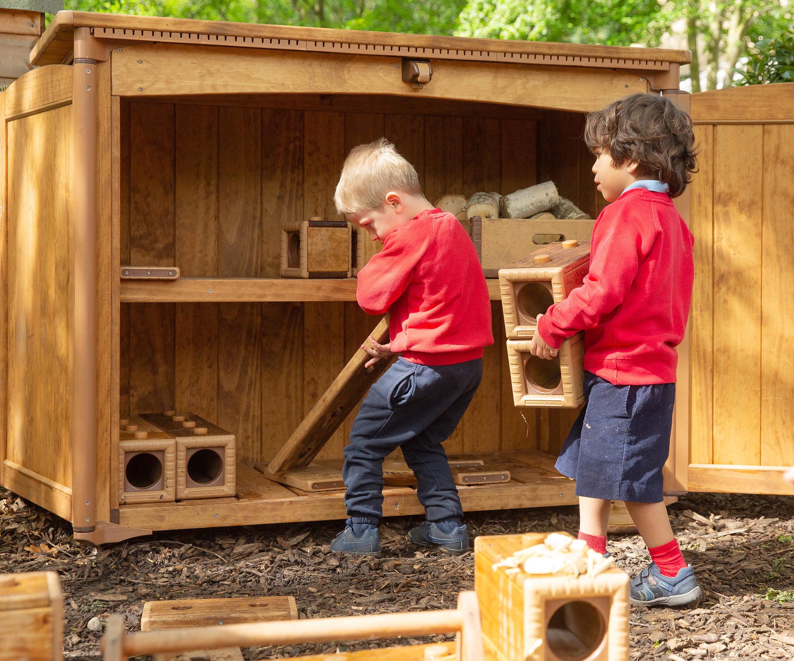 Two nursery aged boys putting Outlast blocks in an Outlast storage unit.