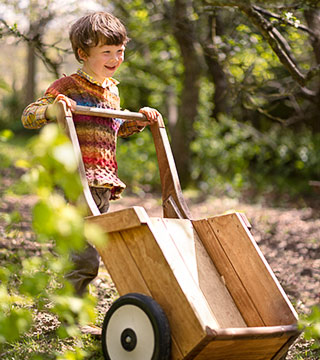 Ein Junge kippt einen kleinen Holzschubkarren aus