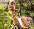 A boy pushing an Outlast wheelbarrow through the woods