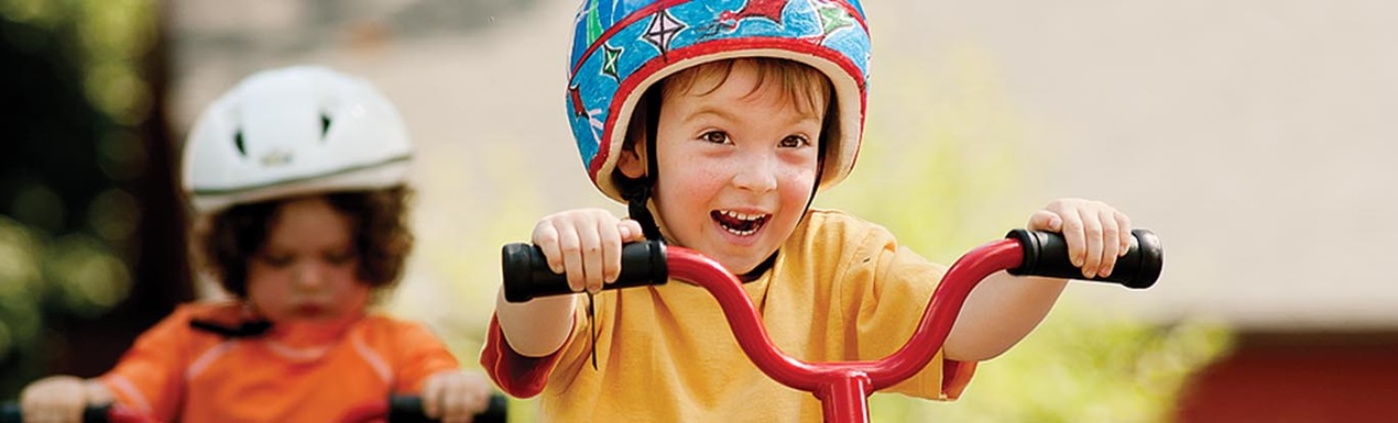 Ein Junge mit Helm fährt auf einem roten Dreirad