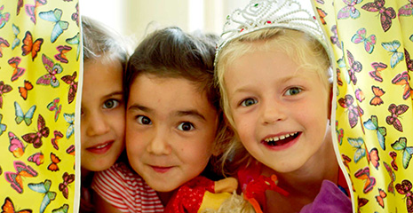 Drei Mädchen schauen durch einen Vorhang und lachen