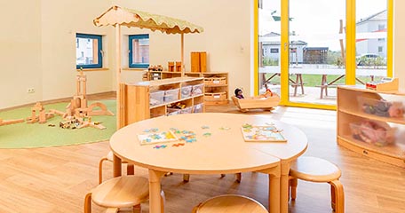 Ein neuer Kindergartenraum, ausgestattet mit Tischen, Stühlen, Hockern und Regalen aus Massivholz.