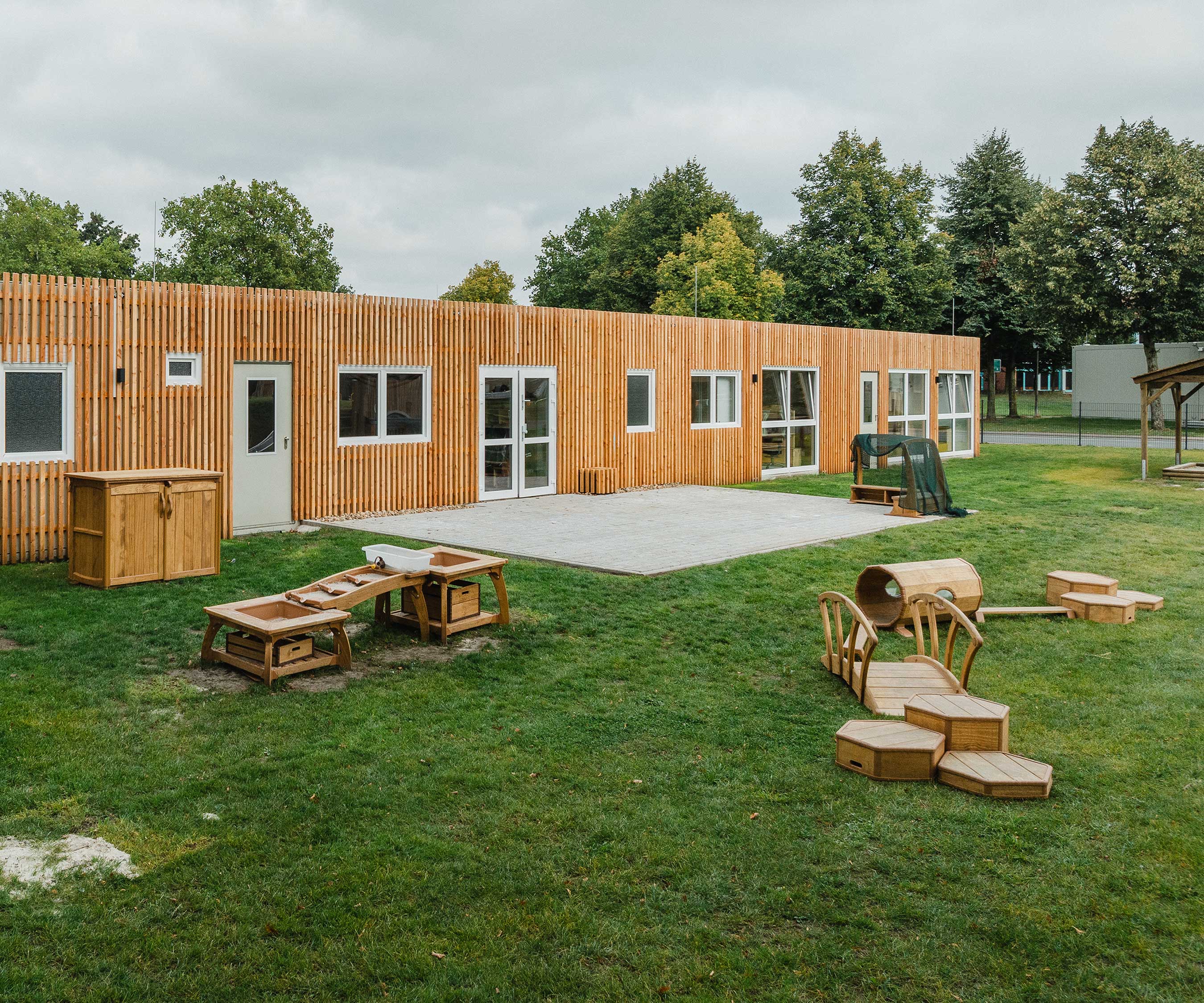 Ein Au&amp;#223;enbereich eines Kindergartens, der mit einer Kaskade f&amp;#252;r Wasserspiele und Outlast Podesten sowie einem Tunnel und einer Br&amp;#252;cke f&amp;#252;r Bewegungsspiele ausgestattet ist.
