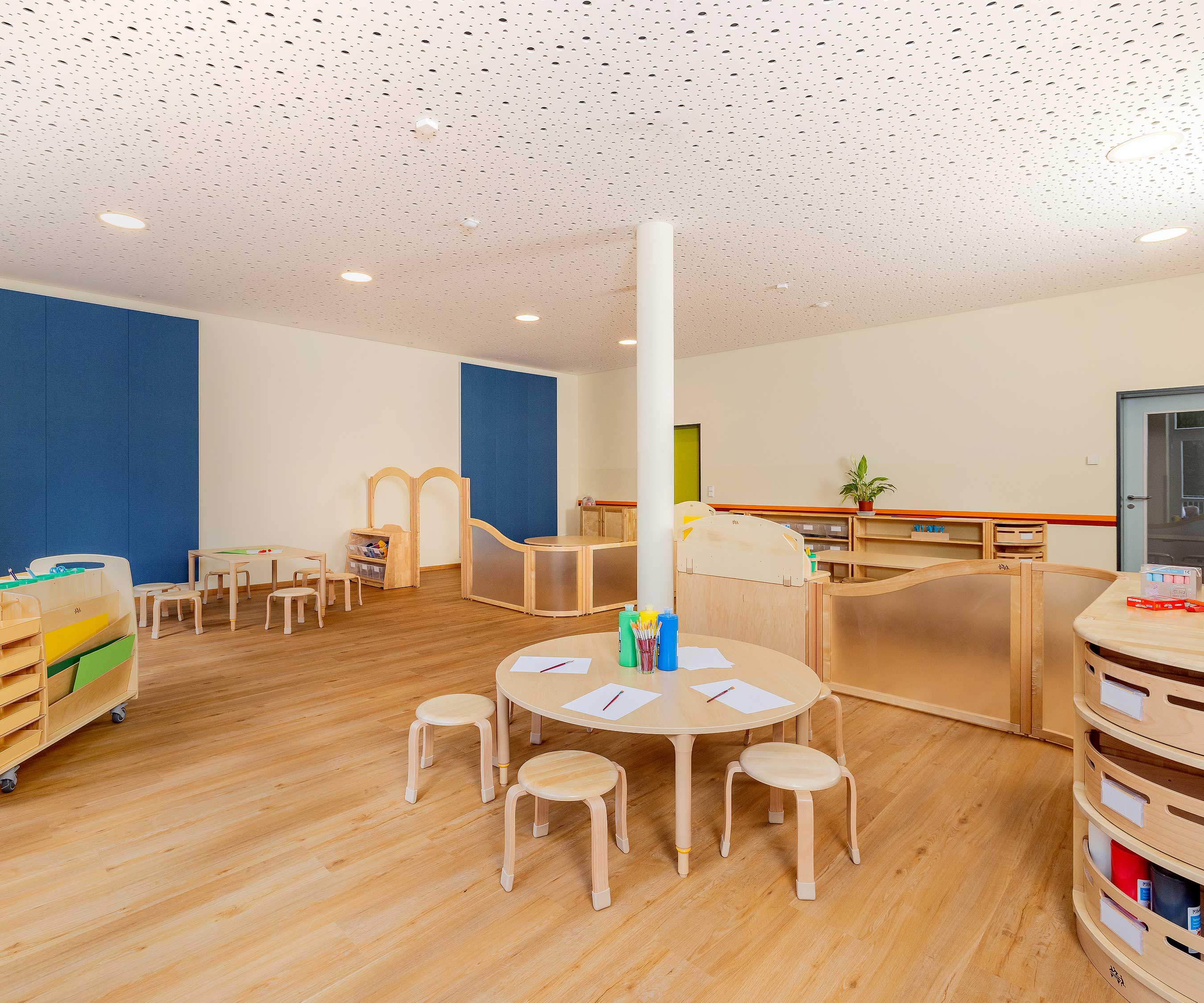 Raumteiler aus Massivholz schaffen einen Kreativbereich um einen runden Tisch mit Kunstmaterialien