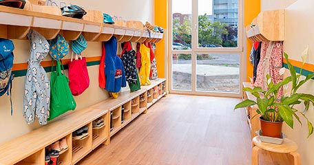 Ein aufgeräumter Garderobenbereich in einer Kita mit den Jacken und Schuhen der Kinder