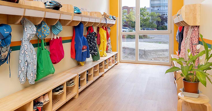 Ein aufgeräumter Garderobenbereich in einer Kita mit den Jacken und Schuhen der Kinder